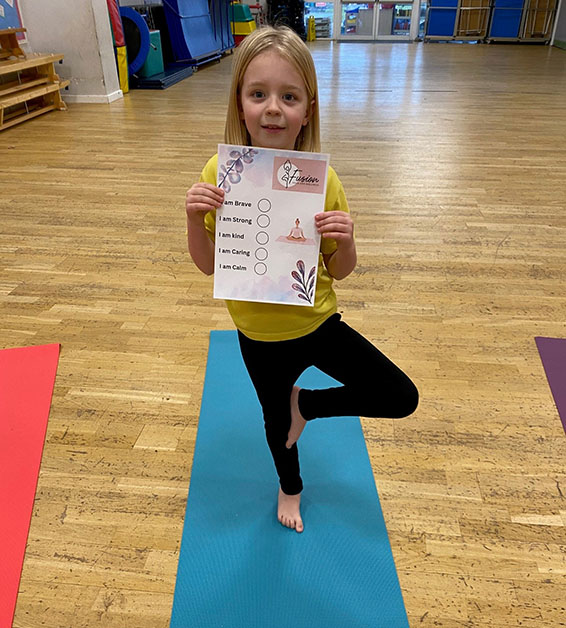 A young girl studying yoga in a yoga class